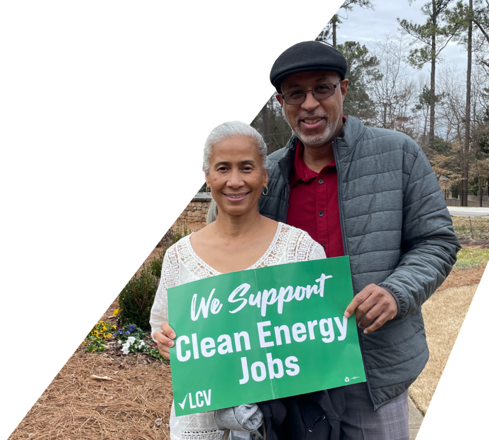 A couple holding a green LCV sign that reads We Support Clean Energy Jobs