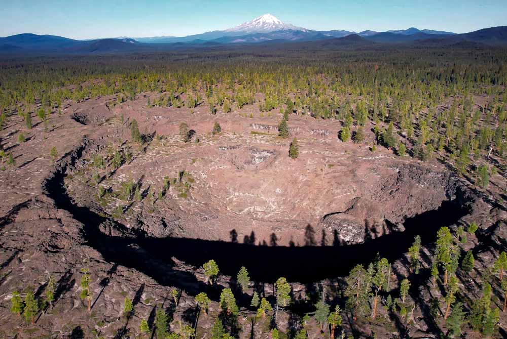 Double Hole Crater at Sáttítla Highlands National Monument surrounded by trees with Mt. Shasta in the distance